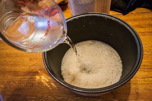 Pouring water into the rice cooker bowl/container.