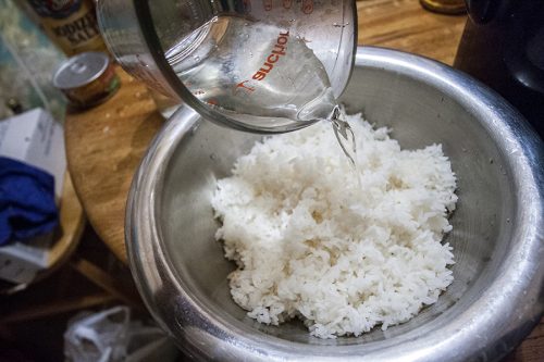 Pouring the rice vinegar mixture over the cooked rice.